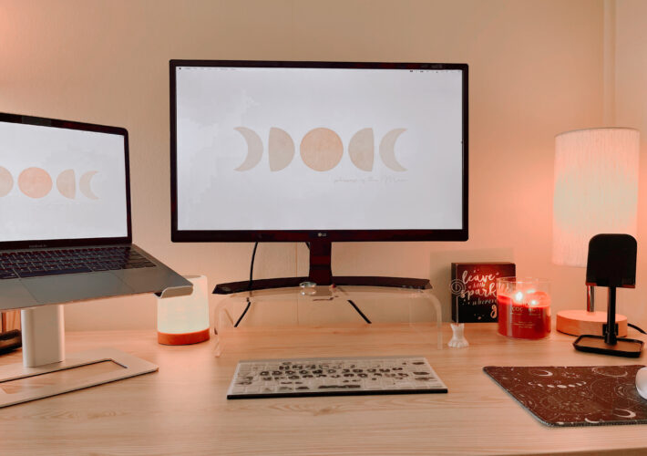 Desktop setup with monitor, laptop, keyboard, lighting and candle